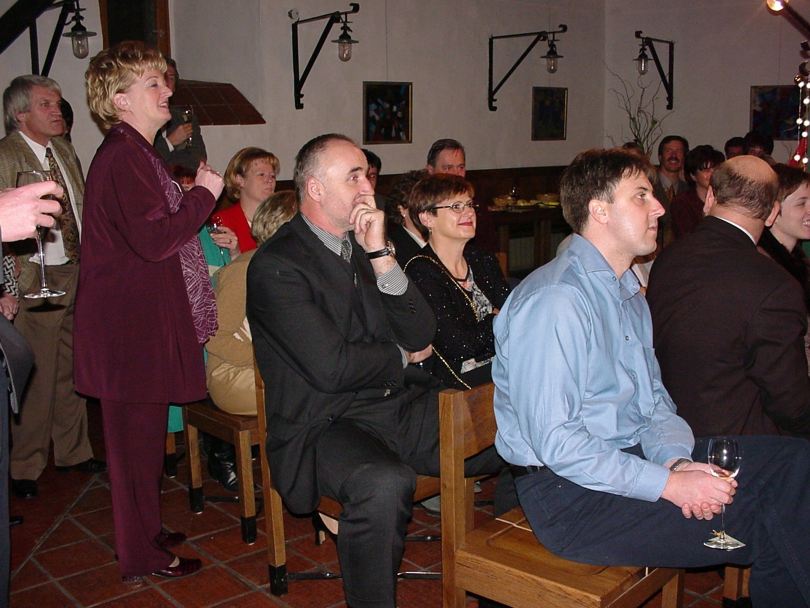 Gosti na obletnici podjetja sedijo in poslušajo program med organizacijo dogodka v dvorani.