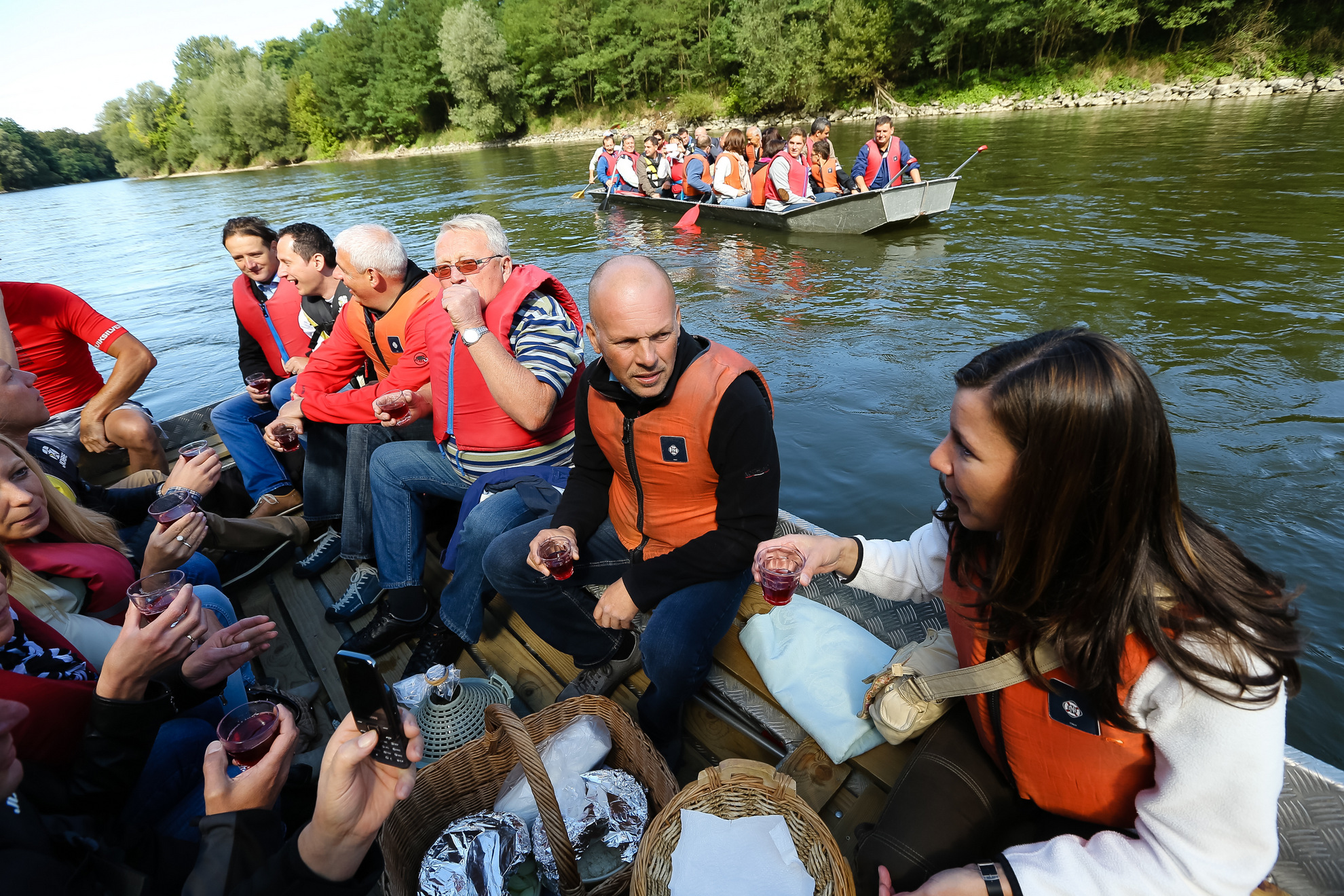 Ljudje v rešilnih jopičih na splavu med družabnim dogodkom na reki.