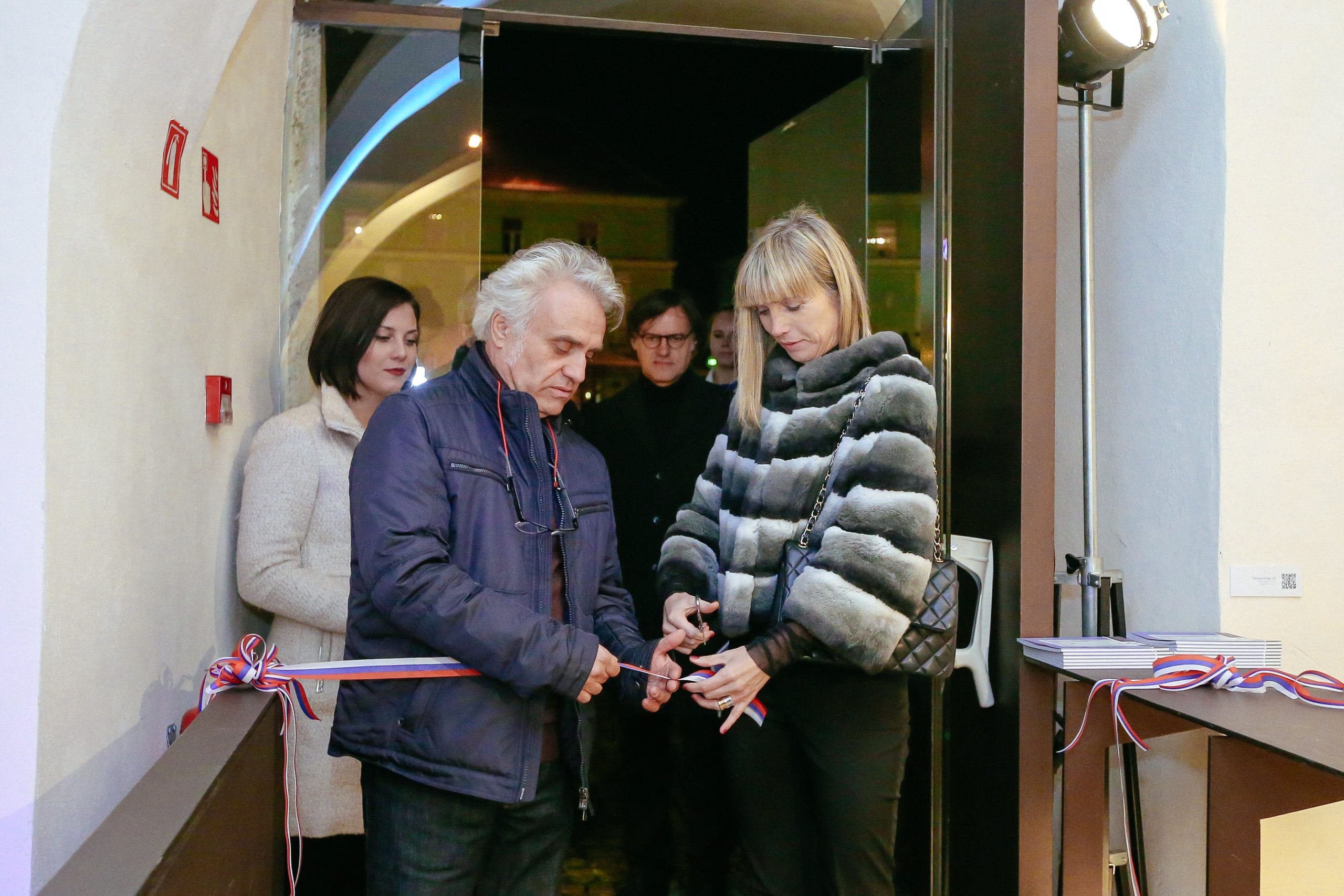 Moški in ženska režeta trobojni trak na uradni otvoritvi dogodka.